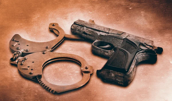 Gun and handcuffs on table. Photo in old color image style — Stock Photo, Image