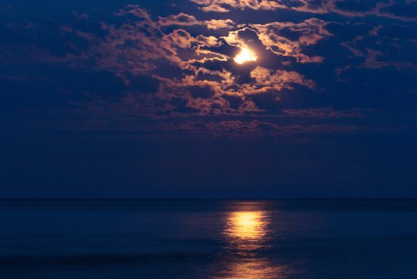 Full moon in night sky over moonlit water