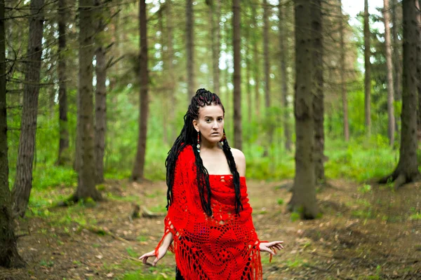 Girl with dreadlocks wrapped in a red knitted scarf in a forest — Stock Photo, Image