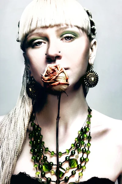 Schöne junge blonde Frau mit einer Rose berühren ihre Lippen und gr — Stockfoto