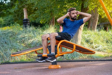 Adam şehir parkındaki açık hava spor salonunda basını sallıyor.