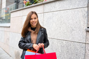 Alışverişe. Alışveriş çantalı güzel bir kadın sokakta yürüyor. Mutlu yaşam tarzı, tatil indirimleri, sezon satışları konsepti..