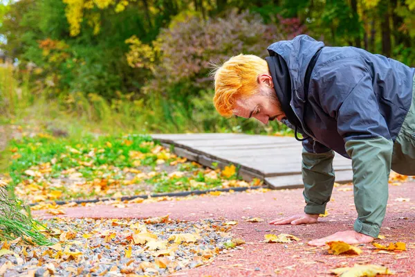 Şınav. Güz parkında şınav çeken şık saçlı bir adam. Açık hava eğitimi konsepti. Boşluğu kopyala.