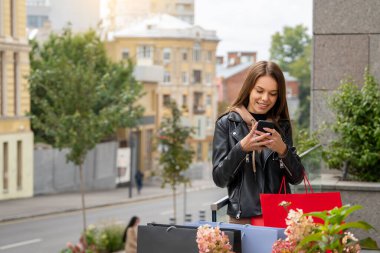 Gülümseyen kadın balkonda dururken telefonda bir mesaj yazar..