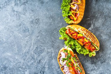 Mutfak masasında farklı malzemelerle ızgara sosisli sandviç..