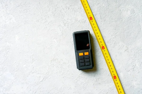 コンクリートの背景に古典的な機械式テープ測定とレーザーテープ測定 — ストック写真