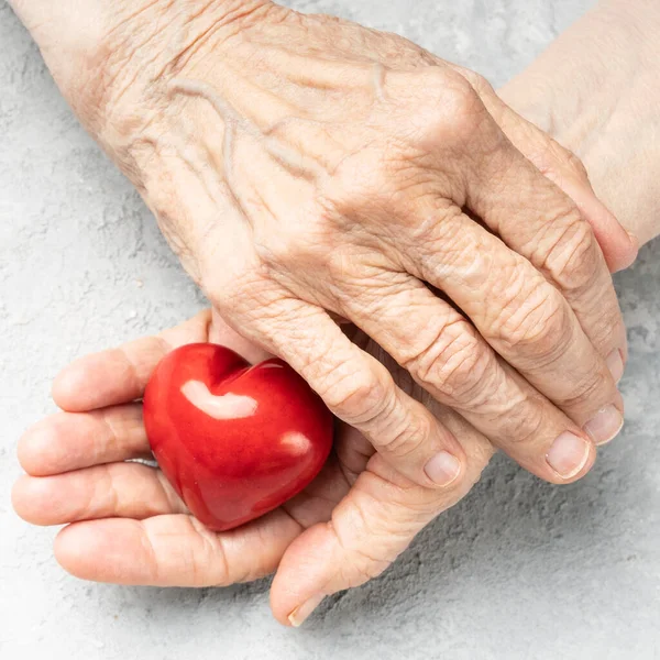 Salud Cardiaca Ancianos Manos Arrugadas Sosteniendo Símbolo Rojo Del Corazón — Foto de Stock