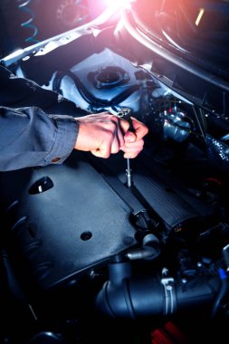 Auto service. Car engine repair. Mechanic removes the engine cover. Vertical photography.