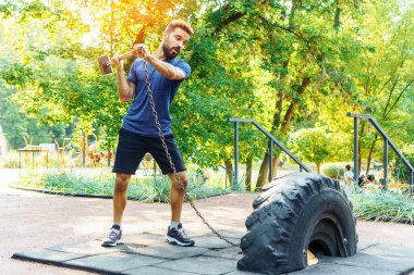 Boks çekiç egzersizi. Genç dövüşçü balyozla lastiğe vurur.. 