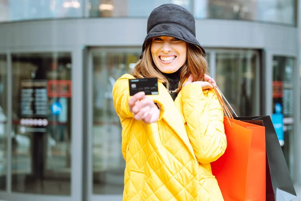 带着购物袋和信用卡在商场背景下开心地大笑的女人 — 图库照片