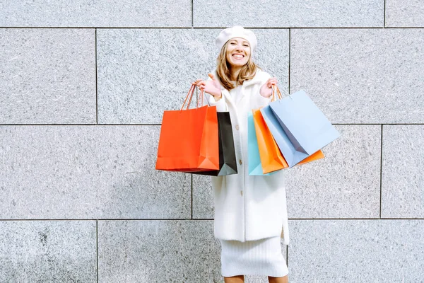 一个带着购物袋靠着石墙的快乐的年轻女子的画像 良好的购物理念 — 图库照片