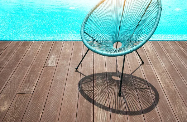夏天的心情背景 靠近游泳池边的柳条椅子 椅子上的一个美丽的影子落在一个木制的阳台上 — 图库照片