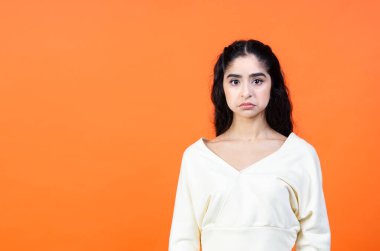 Sorunlar konsepti. Turuncu arka planda, fotokopi alanı olan üzgün bir genç kadının portresi..