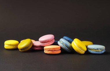 Siyah arkaplanda fotokopi alanı olan renkli Fransız kurabiyeleri.