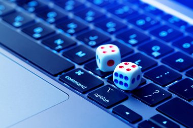 Kumar geçmişi. Çevrimiçi kumarhane, online oyun konsepti. Oyun zarları modern bir dizüstü bilgisayarın klavyesinde yatıyor..