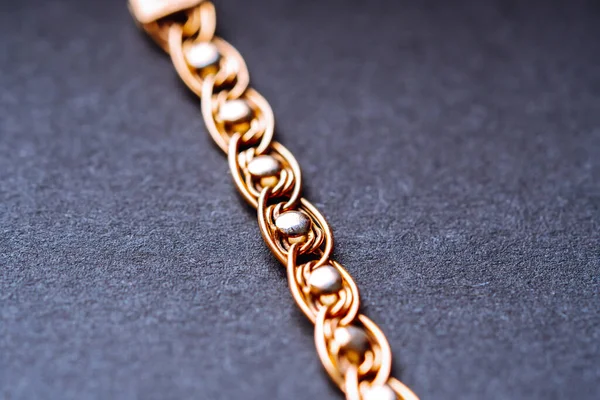 The structure of the weaving of a gold chain bracelet. Golden wristband. Soft focus.