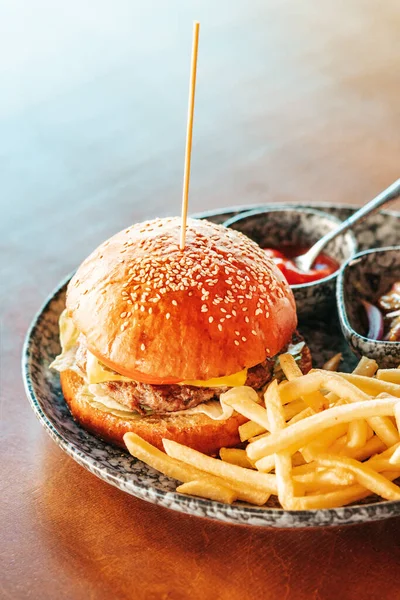 Tasty burger. Hot hamburger with french fries and ketchup are on the table. Vertical composition.