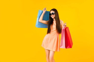 Fashion asian woman holding shopping bags on a yellow background with copy space. Summer sales concepts.