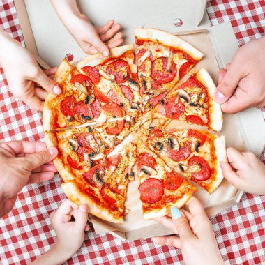Pizza hands. Several hands take pizza at the same time, view above. Hot tasty take out pizza from the box for group of people. Square composition. 