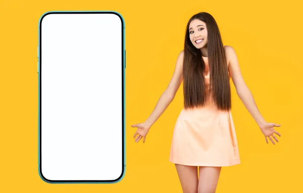I don\'t know. Positive puzzled asian girl with arms to the sides and a funny smile on a yellow background. Posing on camera, shrugging shoulders, copy space.
