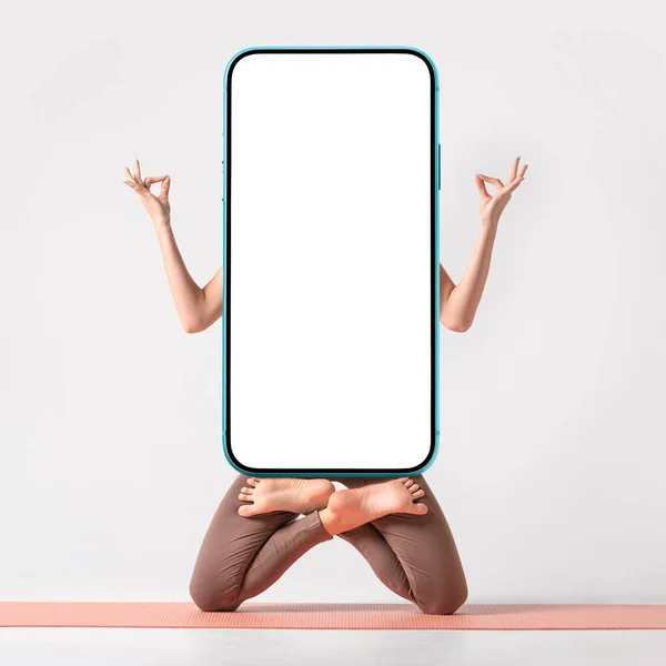 Yoga or fitness creative application blank for your design. Fit woman practicing yoga, keeping balance, while standing on a knees in a difficult lotus pose and holding modern smartphone with empty white screen. Square composition.