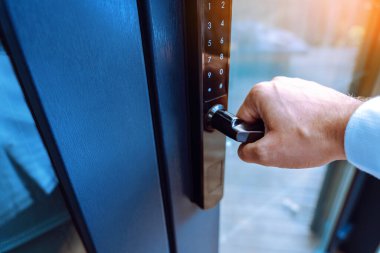 Male hand holding a handle of key free smart lock. Keyless access to home or hotel.
