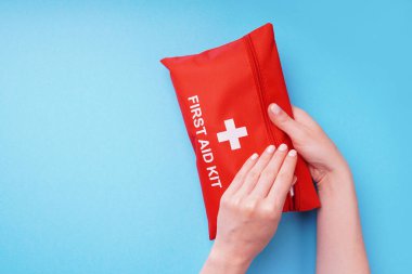 Mavi arka plandaki ilk yardım çantası kadınların elinde..