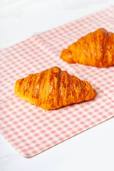 Fresh baked french croissants lying on the table. Vertical photo.
