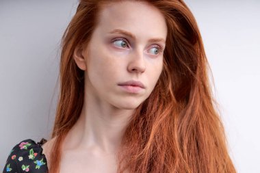 Uzun saçlı, rüya gibi kızıl saçlı kadın. Yan tarafa bakıyor. Düşünüyor, beyaz tenli.