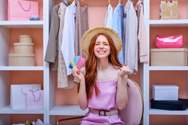 Sevimli, hoş görünümlü, neşeli bir bayan elinde kredi kartı tutuyor. İnternetten alışveriş yapmaktan mutlu.