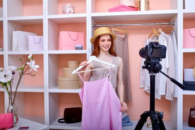 Gülümseyen genç kadın yeni pembe kokteyl elbisesiyle ilgili video bloğu bölümü kaydediyor.