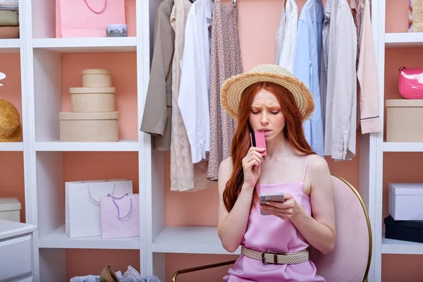 Нервная рыжеволосая женщина, использующая приложения для покупок на смартфоне, делающая онлайн покупки — стоковое фото