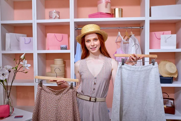 Ev dolabı. Güzel, kızıl saçlı bir kadın moda kıyafetlerini seçiyor. Alışveriş konsepti.