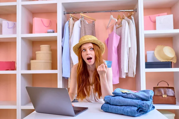 온라인 쇼핑을 위해 랩탑을 사용하여 집에 앉아 있는 새 옷을 사는 여성 — 스톡 사진