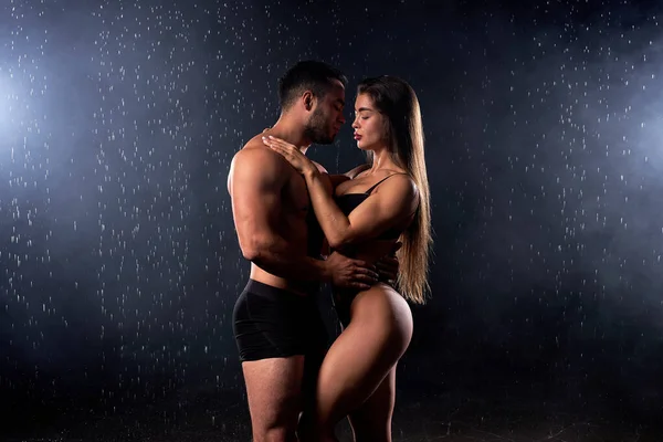 Портрет страстной красивой пары, обнимающейся под сильным дождем на черном фоне — стоковое фото