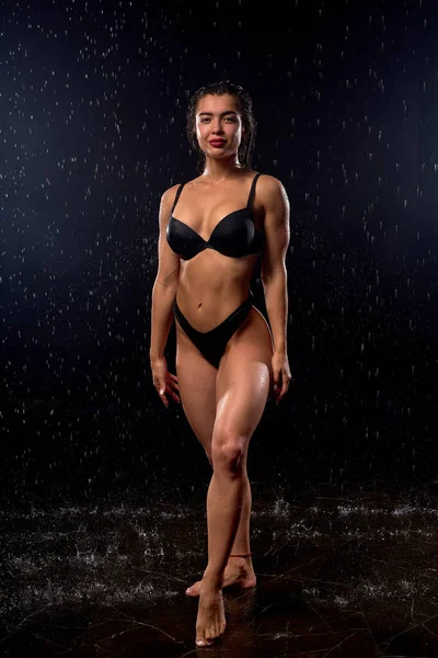 Atleta bagnato alta donna magra indossa lingerie nera in posa in gocce d'acqua piovana — Foto Stock