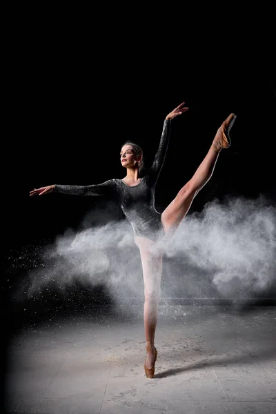Ballerina che posa danzando con grazia in studio con nuvola di polvere, farina. — Foto Stock