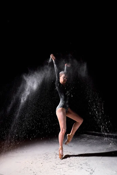 Hermosa bonita hembra vistiendo negro gimnasia body bailando con volando en polvo — Foto de Stock