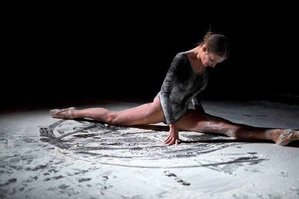 Vue latérale sur Ballet femme flexible danseuse assise dans la pose de ballet avec de la farine. — Photo