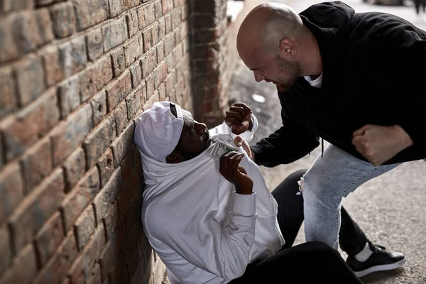 Vista lateral sobre el bandido caucásico Hooligan exigiendo dinero a un extraño africano — Foto de Stock