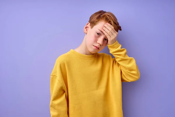 Trauriger Junge leidet unter Kopfschmerzen, berührt Kopf, isoliert auf violettem Hintergrund — Stockfoto