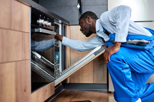 Gerichte man of dienst werknemer in speciale kleding installeert, demonteert vaatwasser — Stockfoto