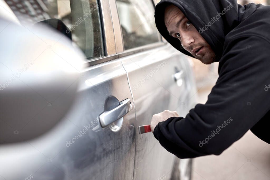 Profile side view of car thief guy, looking around, afraid to be caught, at street