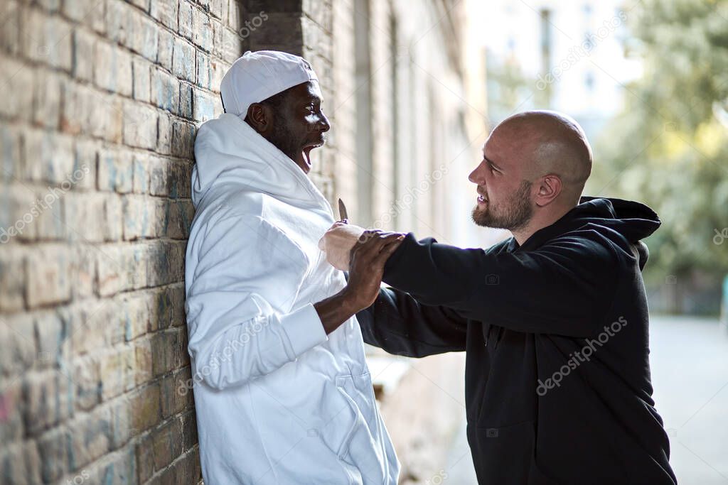 Side View on Young Black Man Scared Of Caucasian Bandit Hooligan At Street