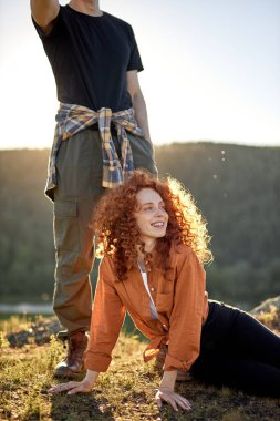 Romantik bir çift genç insan dağların tepesinde dinleniyor, gün ışığında poz veriyorlar.