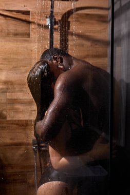 Tutkuyla kucaklaşan ve birlikte duş alan çok ırklı bir çift.