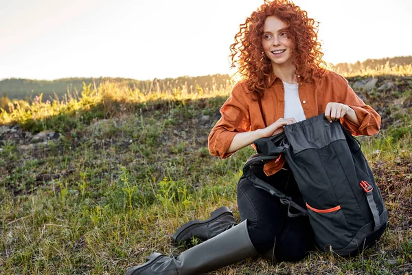 Attarctive csinos hölgy nyitja táska biztosítása utazás, túrázás a természetben vidéken — Stock Fotó