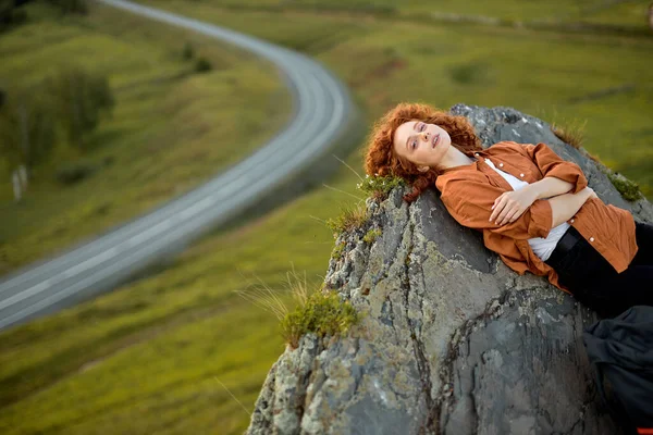 Top view portré gyönyörű vörös hajú hölgy fekszik a hegyi szikla tetején — Stock Fotó