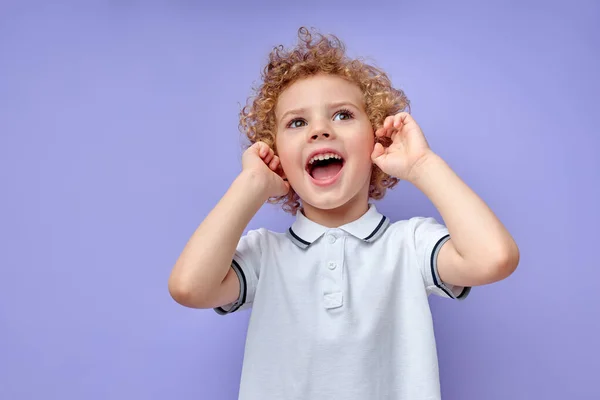 Divertido niño cerrando oídos gritando por asombro aislado sobre fondo púrpura — Foto de Stock