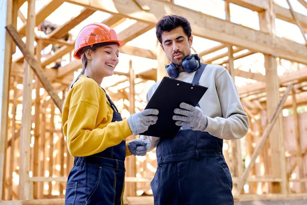 Zwei glückliche Architekten mit Klemmbrettbauplänen auf der Baustelle — Stockfoto